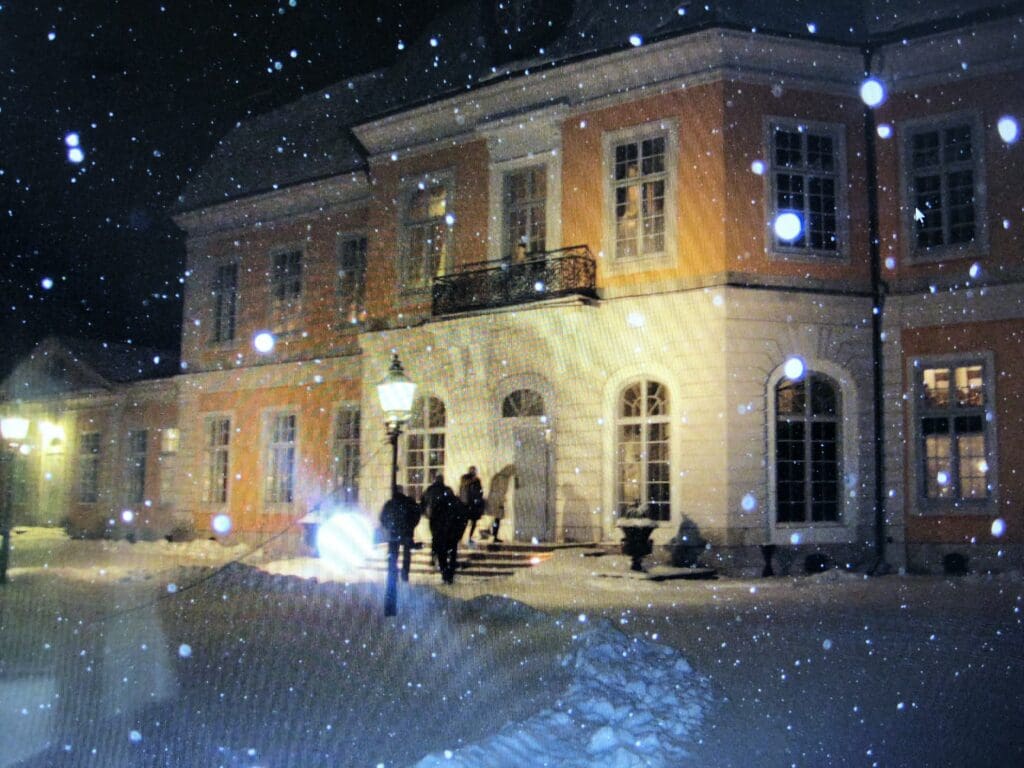 Osterbybruks herrgard upplyst en vinterkvall med snofall