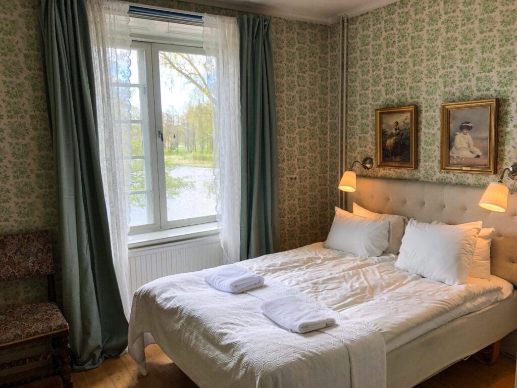 Hotellrum med dubbelsang och fonster mot herrgardsparken